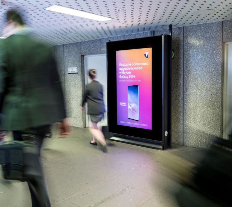 Digital portrait screen in rail station featuring Telstra creative