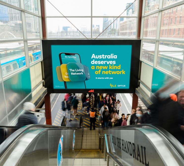 Digital large format billboard in rail train station featuring Optus creative