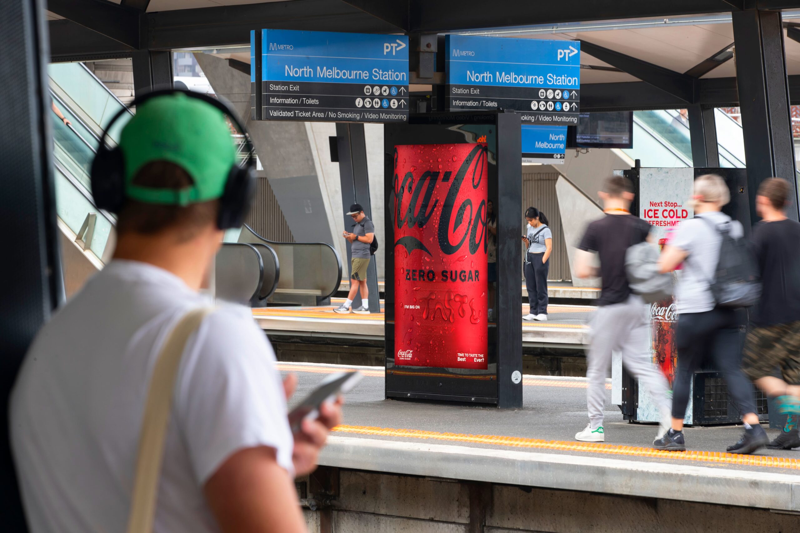 Digital advertising screen at rail station in Melbourne with Coca-Cola creative
